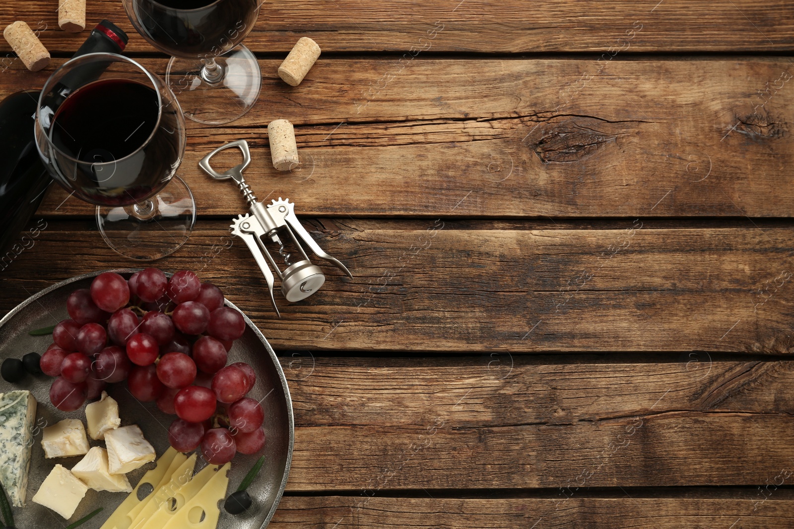 Photo of Tasty red wine and snacks on wooden table, flat lay. Space for text