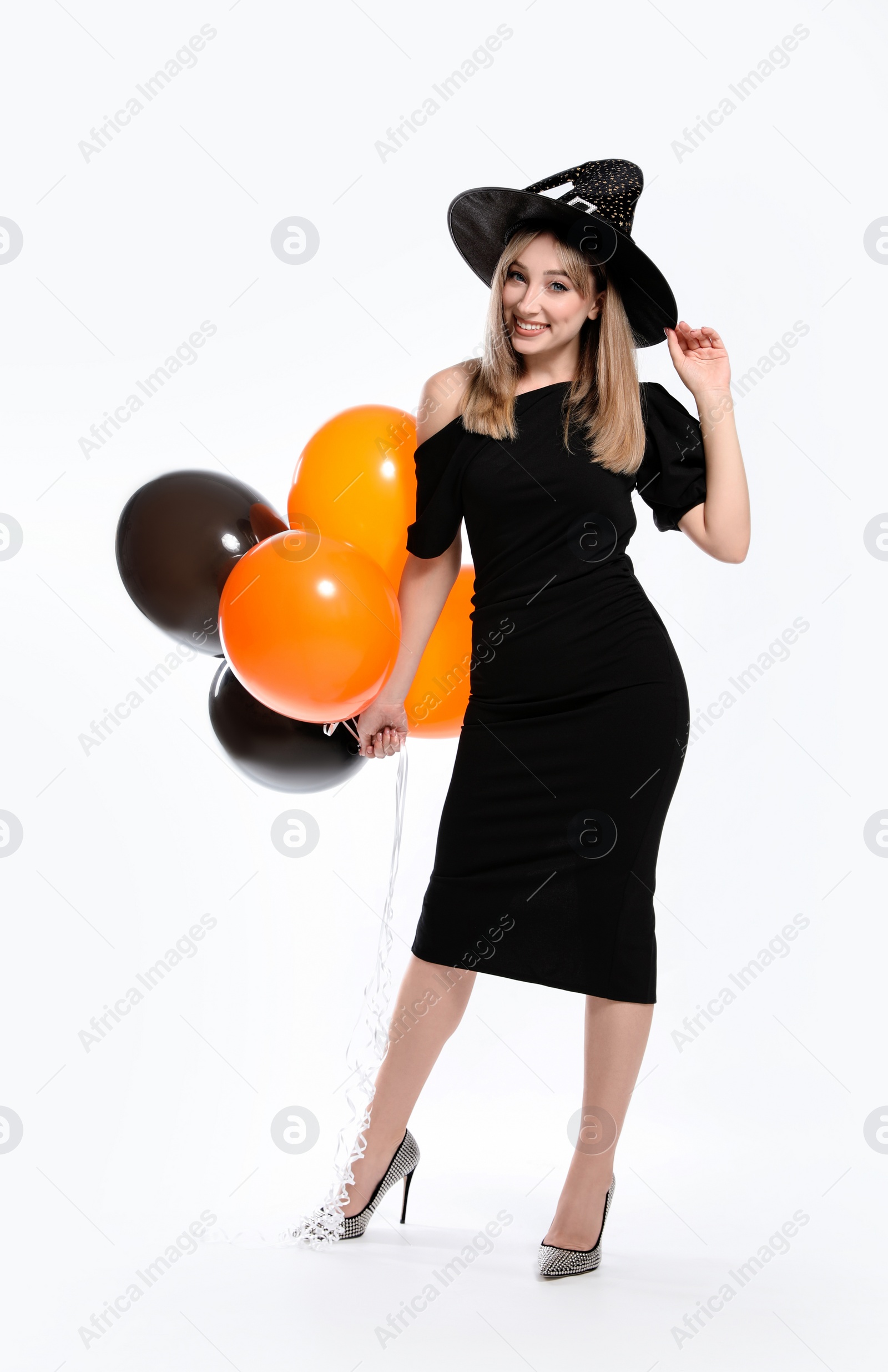 Photo of Beautiful woman in witch costume with balloons on white background. Halloween party