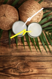 Flat lay composition with glasses of coconut water on wooden background. Space for text