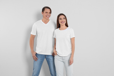 Young couple in stylish jeans on light background