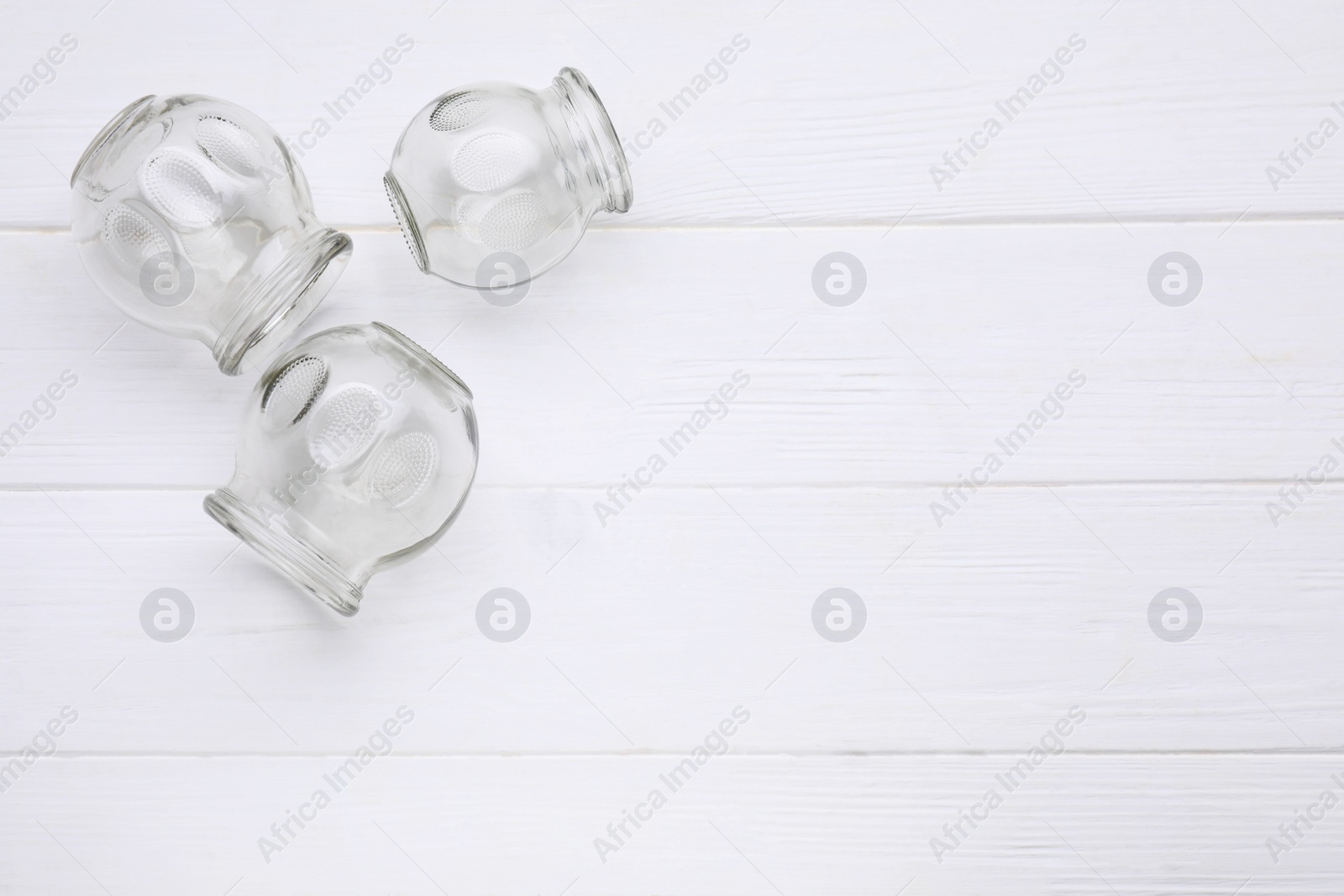 Photo of Glass cups on white wooden table, flat lay with space for text. Cupping therapy