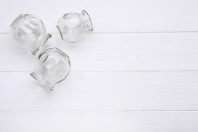 Photo of Glass cups on white wooden table, flat lay with space for text. Cupping therapy