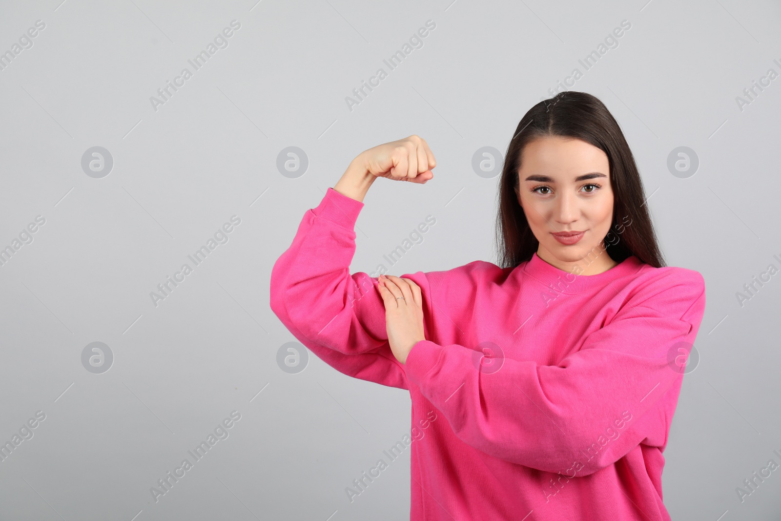 Photo of Strong woman as symbol of girl power on light grey background, space for text. 8 March concept