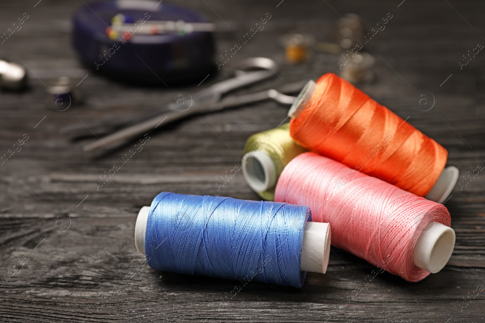 Photo of Sewing threads and accessories on wooden background