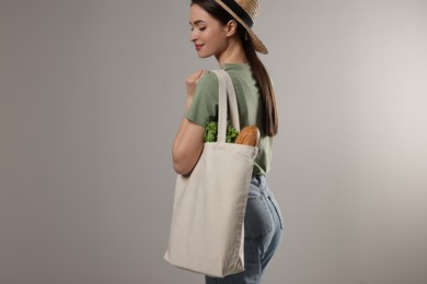 Woman with eco bag full of products on light background