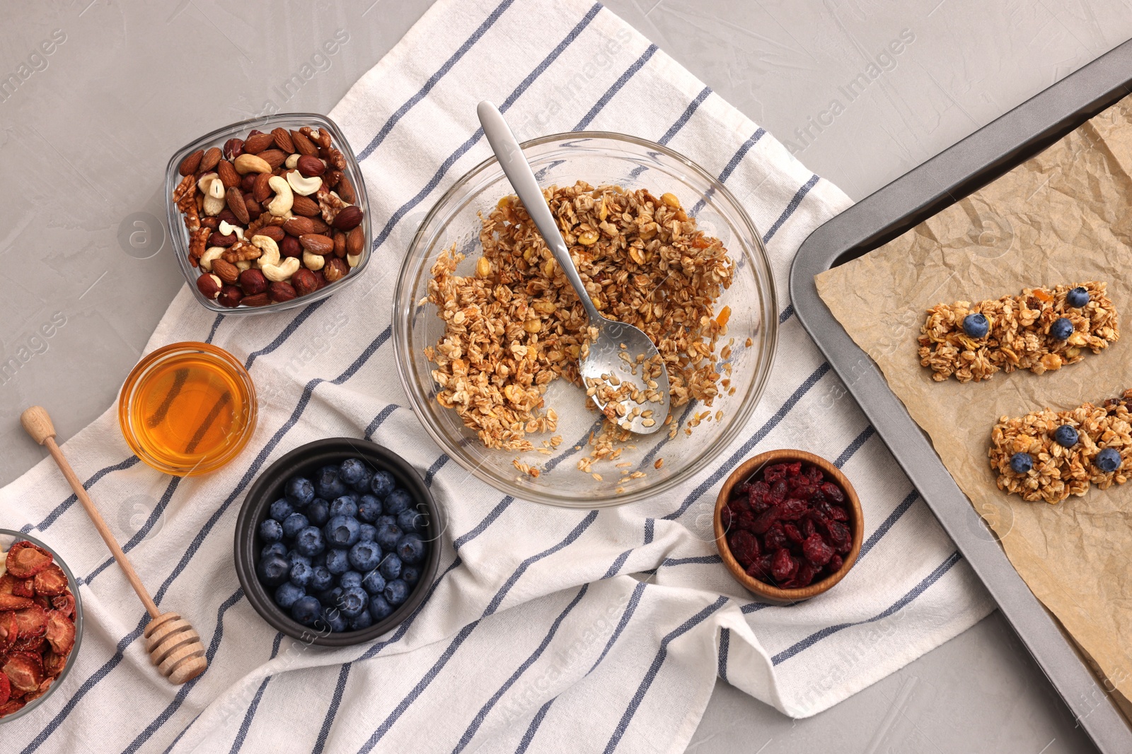 Photo of Making granola bars. Baking tray and ingredients on light grey table, flat lay
