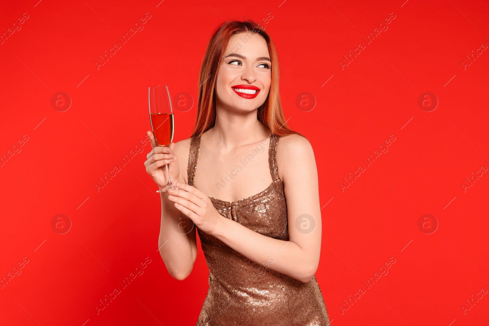 Photo of Young woman in dress with glass of wine on red background