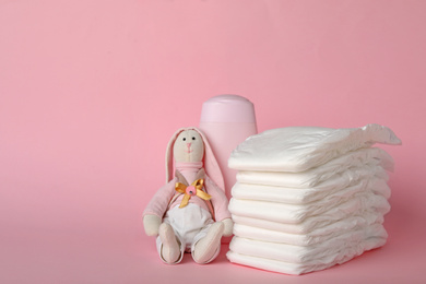 Photo of Diapers and baby accessories on pink background, space for text