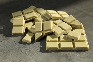 Pieces of tasty matcha chocolate bars on grey textured table, closeup