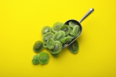 Photo of Scoop with slices of kiwi on color background, top view. Dried fruit as healthy food