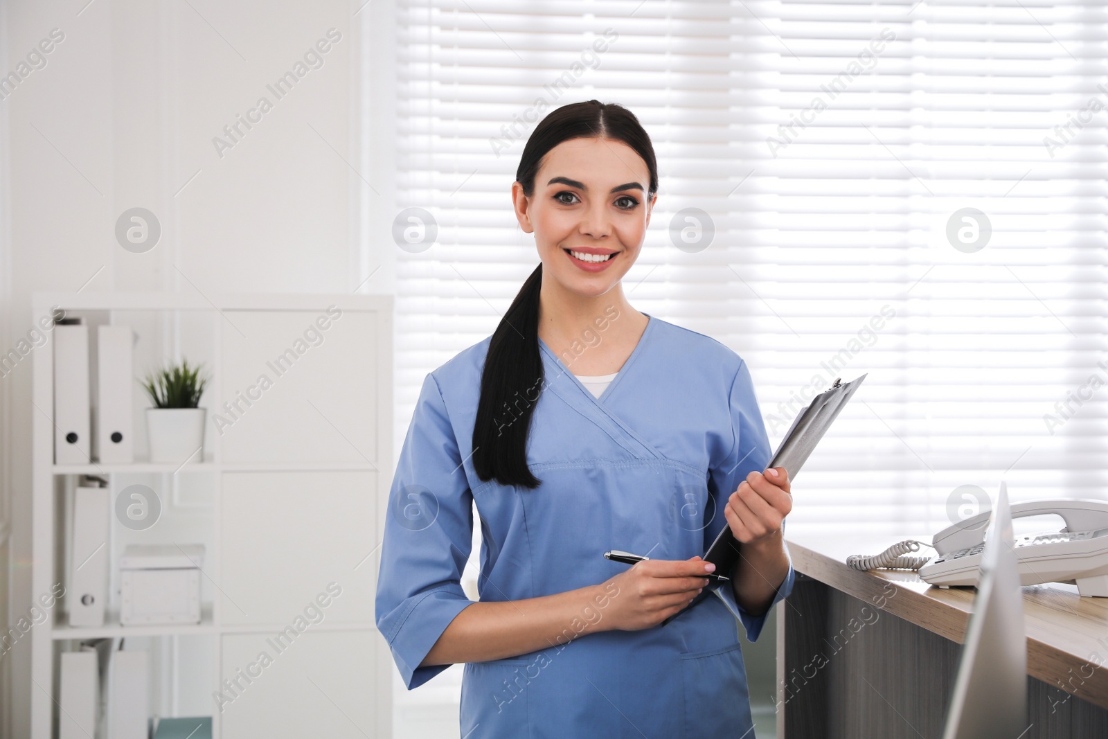 Photo of Receptionist with clipboard at countertop in hospital