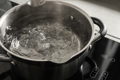 Photo of Pot with boiling water on electric stove in kitchen, closeup