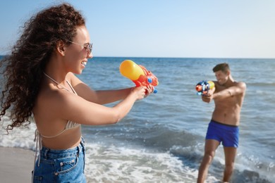 Photo of Couple with water guns having fun on beach