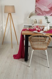 Photo of Color accent table setting. Glasses, plates, pink napkins and vase with green branch in dining room