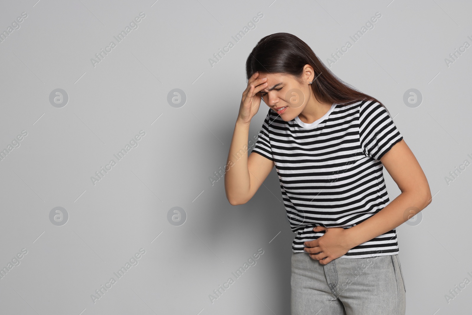 Photo of Young woman suffering from menstrual pain on grey background, space for text