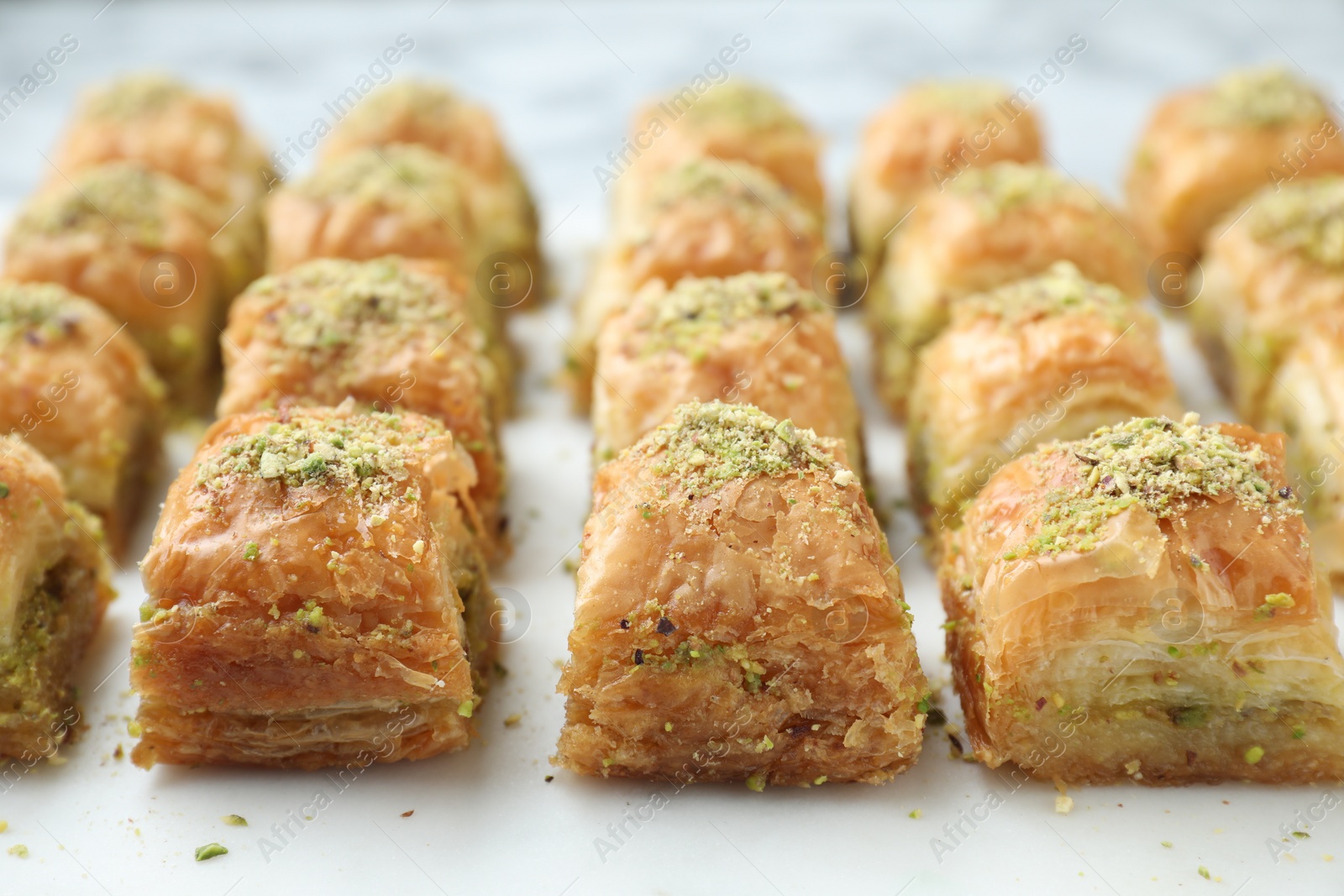 Photo of Delicious fresh baklava with chopped nuts on white table, closeup. Eastern sweets