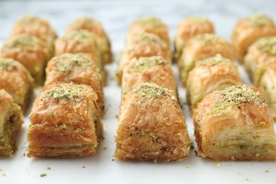 Photo of Delicious fresh baklava with chopped nuts on white table, closeup. Eastern sweets