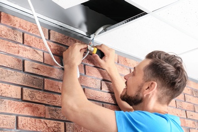 Photo of Male technician installing alarm system indoors