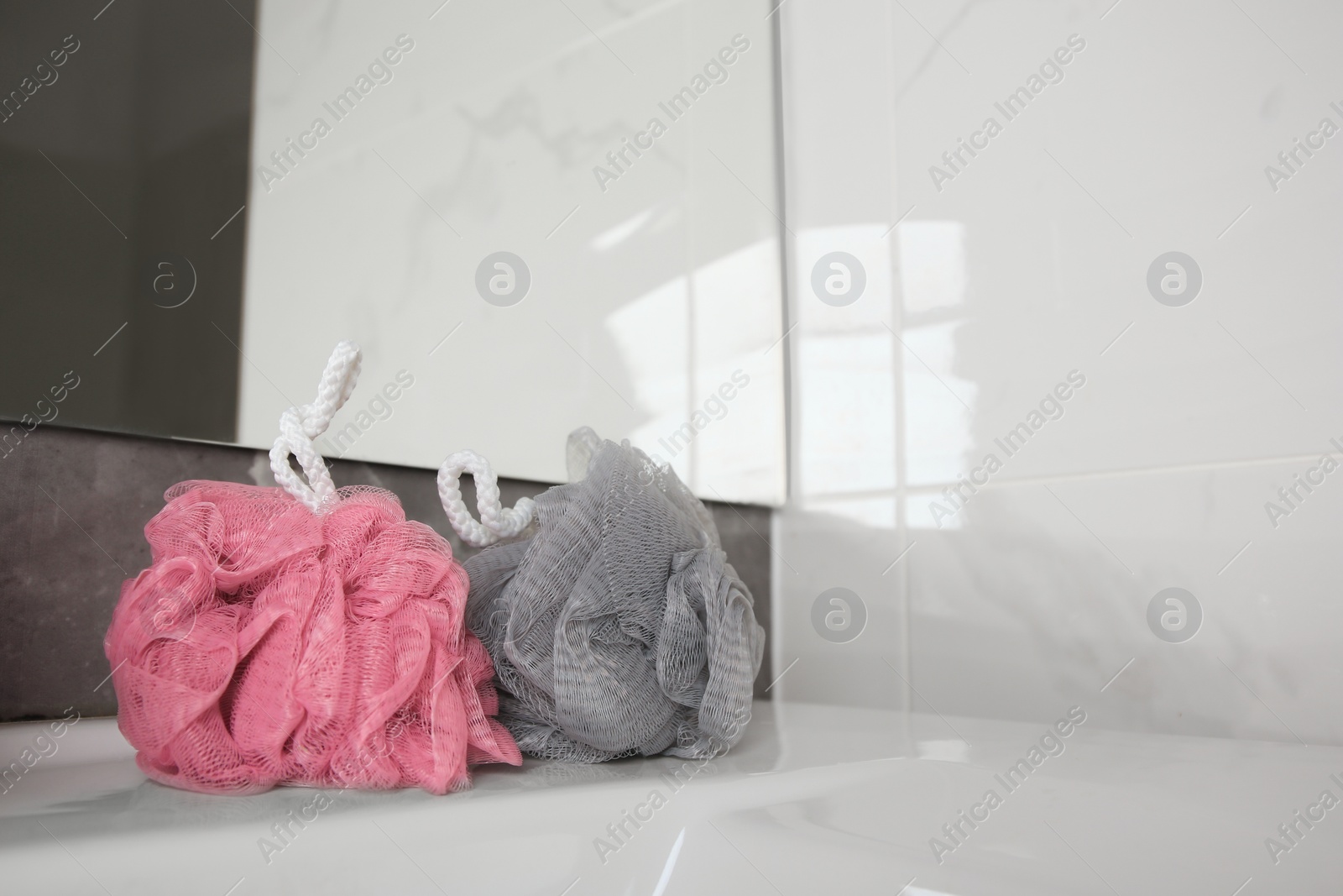Photo of Colorful shower puffs on sink in bathroom, space for text