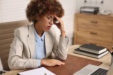 Photo of Woman suffering from headache at workplace in office