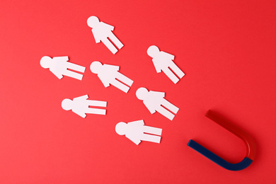 Photo of Magnet and paper people on red background, flat lay