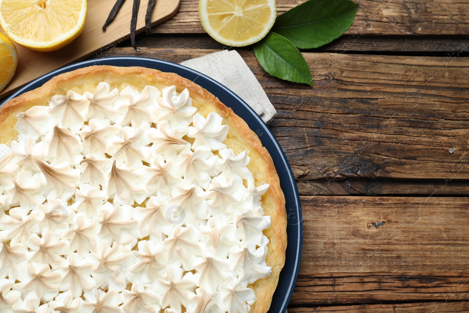 Photo of Flat lay composition with delicious lemon meringue pie on wooden table. Space for text