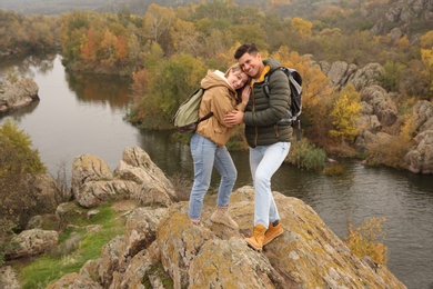 Photo of Couple of hikers on steep cliff in mountains