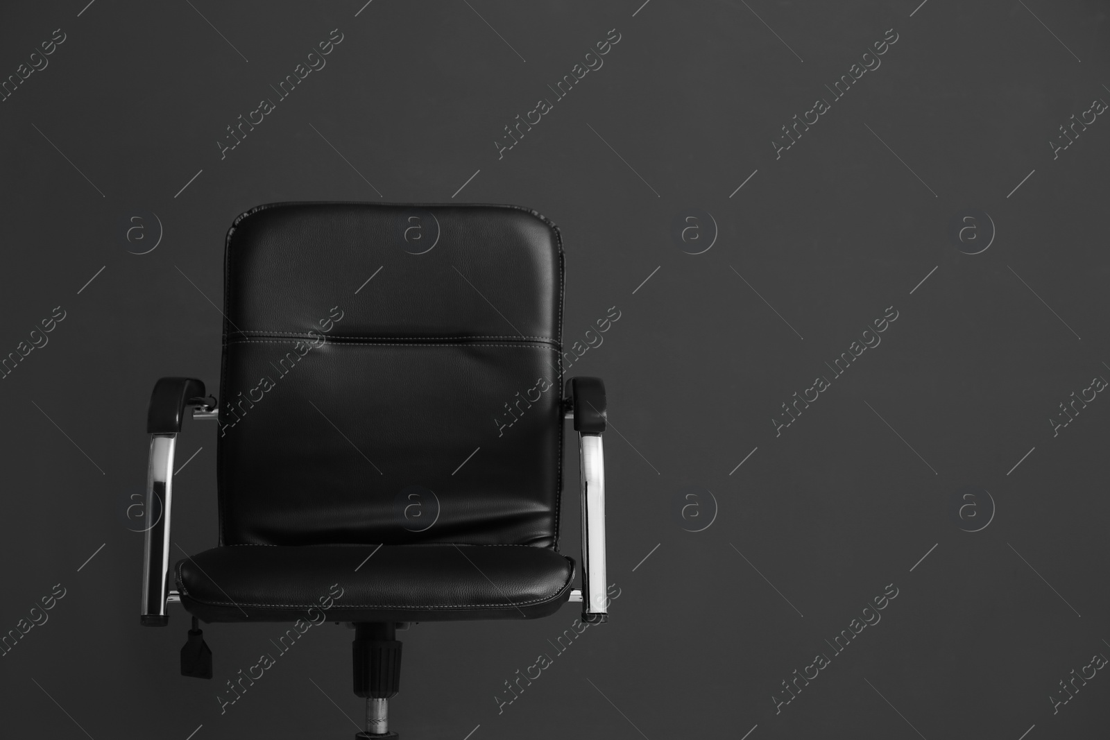 Photo of Comfortable office chair on black background. Space for text