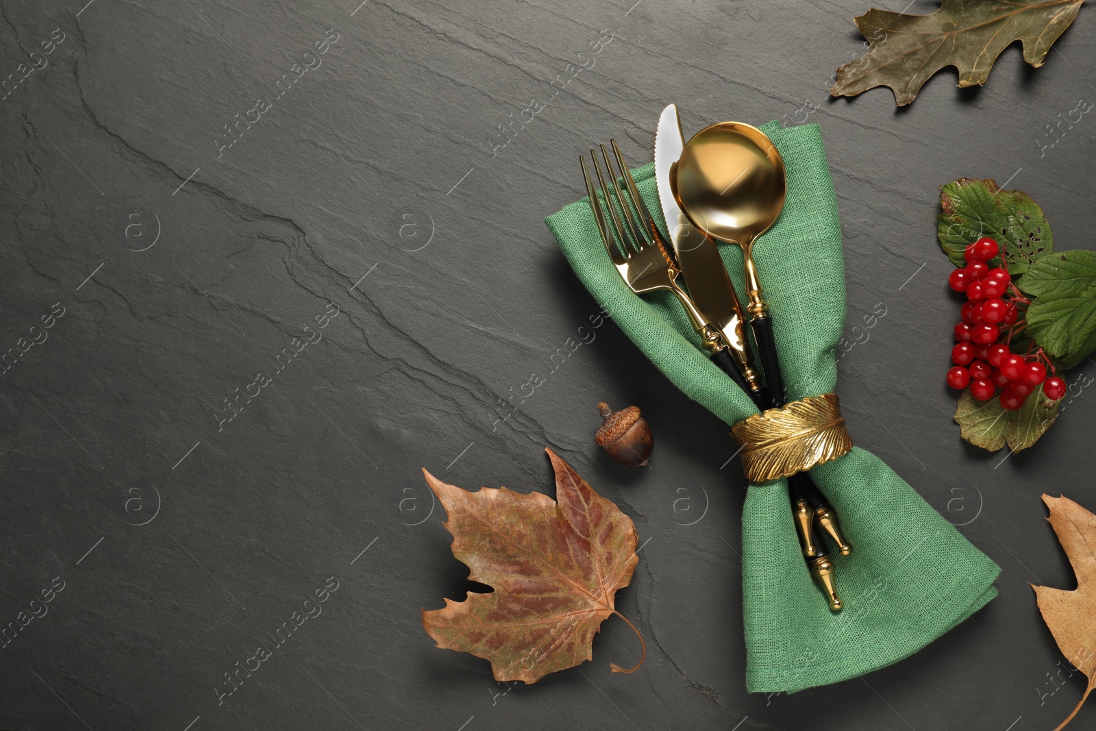 Photo of Autumn table setting. Cutlery, napkin, viburnum berries and leaves on grey textured background, flat lay with space for text