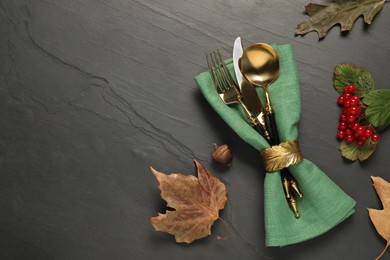 Autumn table setting. Cutlery, napkin, viburnum berries and leaves on grey textured background, flat lay with space for text