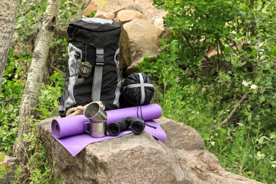 Backpack and camping equipment on stone in forest. Space for text