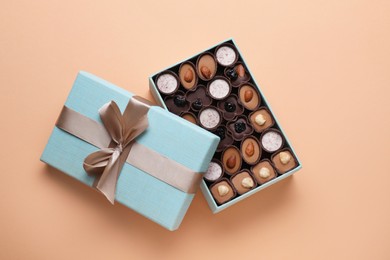 Photo of Open box of delicious chocolate candies on beige background, flat lay