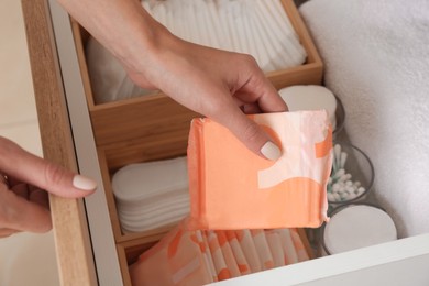 Photo of Woman taking disposable menstrual pad from drawer at home, closeup