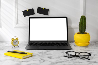 Photo of Office workplace with computer, glasses, houseplant and stationery on marble table near white wall