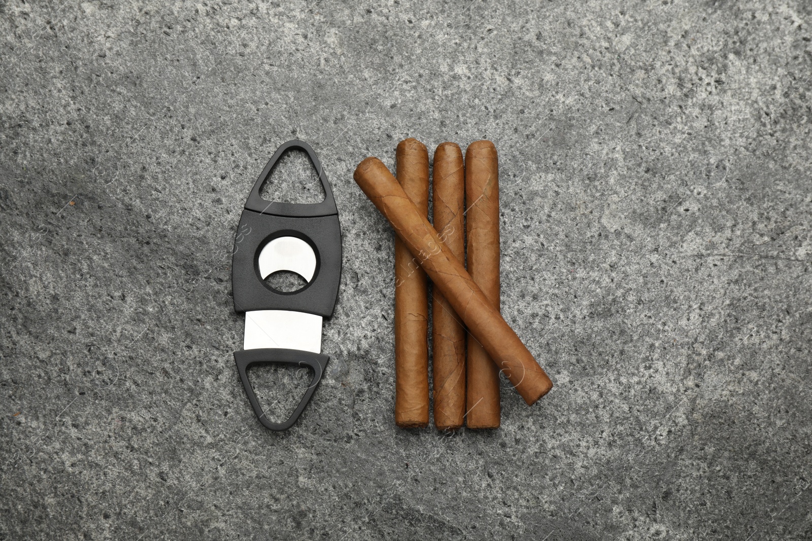 Photo of Cigars and guillotine cutter on grey table, flat lay