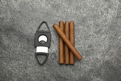 Photo of Cigars and guillotine cutter on grey table, flat lay