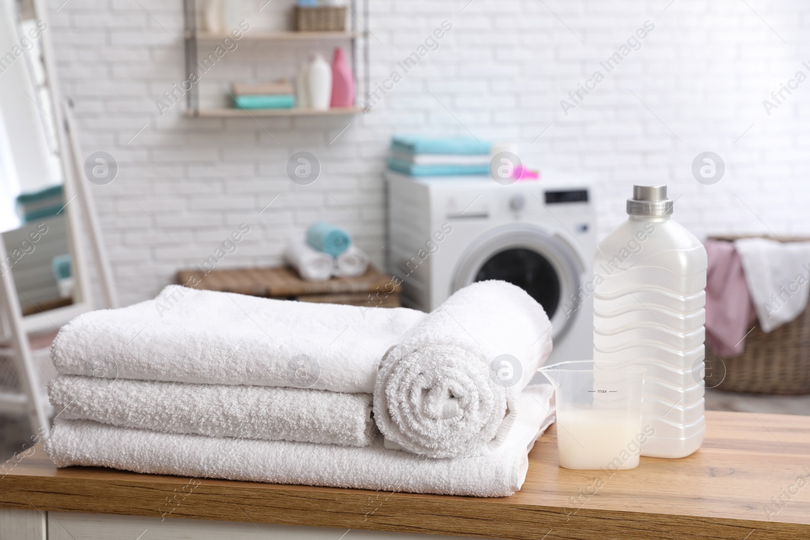 Photo of Soft bath towels and detergent on table against blurred background