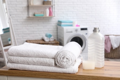 Photo of Soft bath towels and detergent on table against blurred background