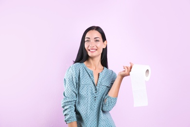 Photo of Beautiful woman holding toilet paper roll on color background