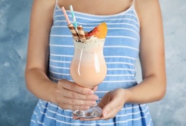 Woman with glass of delicious milk shake on color background, closeup