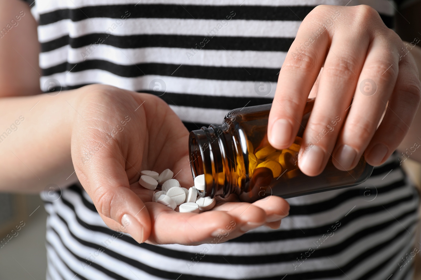 Photo of Woman pouring pills from bottle, closeup view