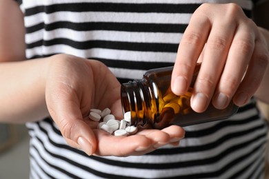 Photo of Woman pouring pills from bottle, closeup view