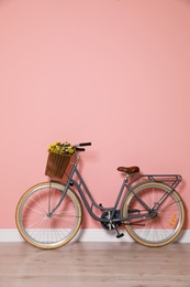 Photo of Retro bicycle with wicker basket near color wall