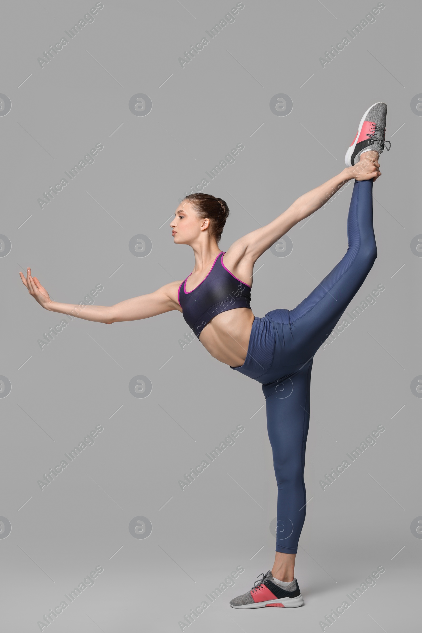 Photo of Woman stretching on grey background. Training exercise