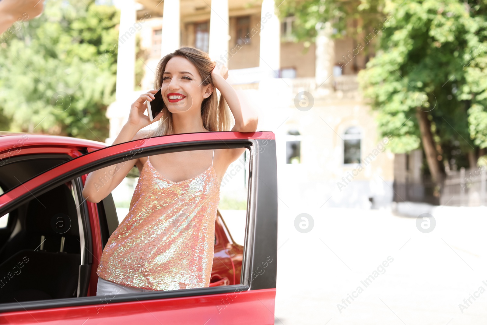 Photo of Young woman talking on phone near car outdoors