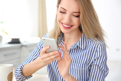 Young woman using phone indoors