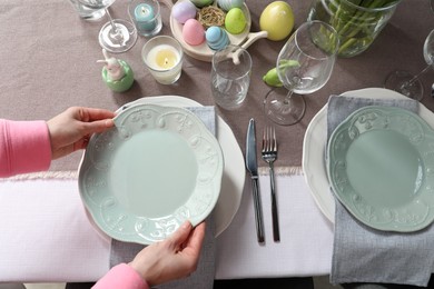 Photo of Woman setting table for festive Easter dinner at home, above view