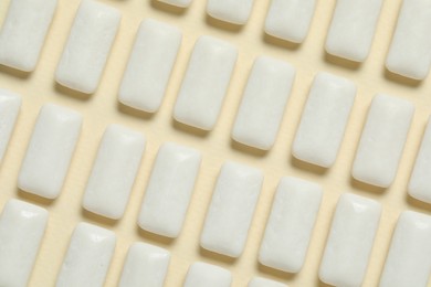 Photo of Tasty white chewing gums on beige background, flat lay