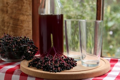 Elderberry drink and Sambucus berries on table near window