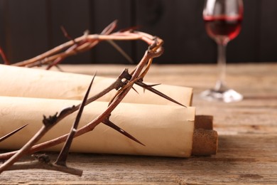 Photo of Crownthorns, old scrolls and glass with wine on wooden table, selective focus